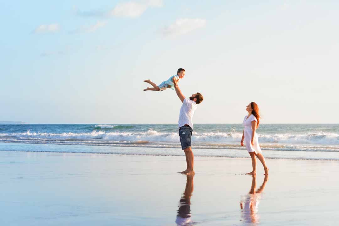 Family on the beach with dad holding their son in the air